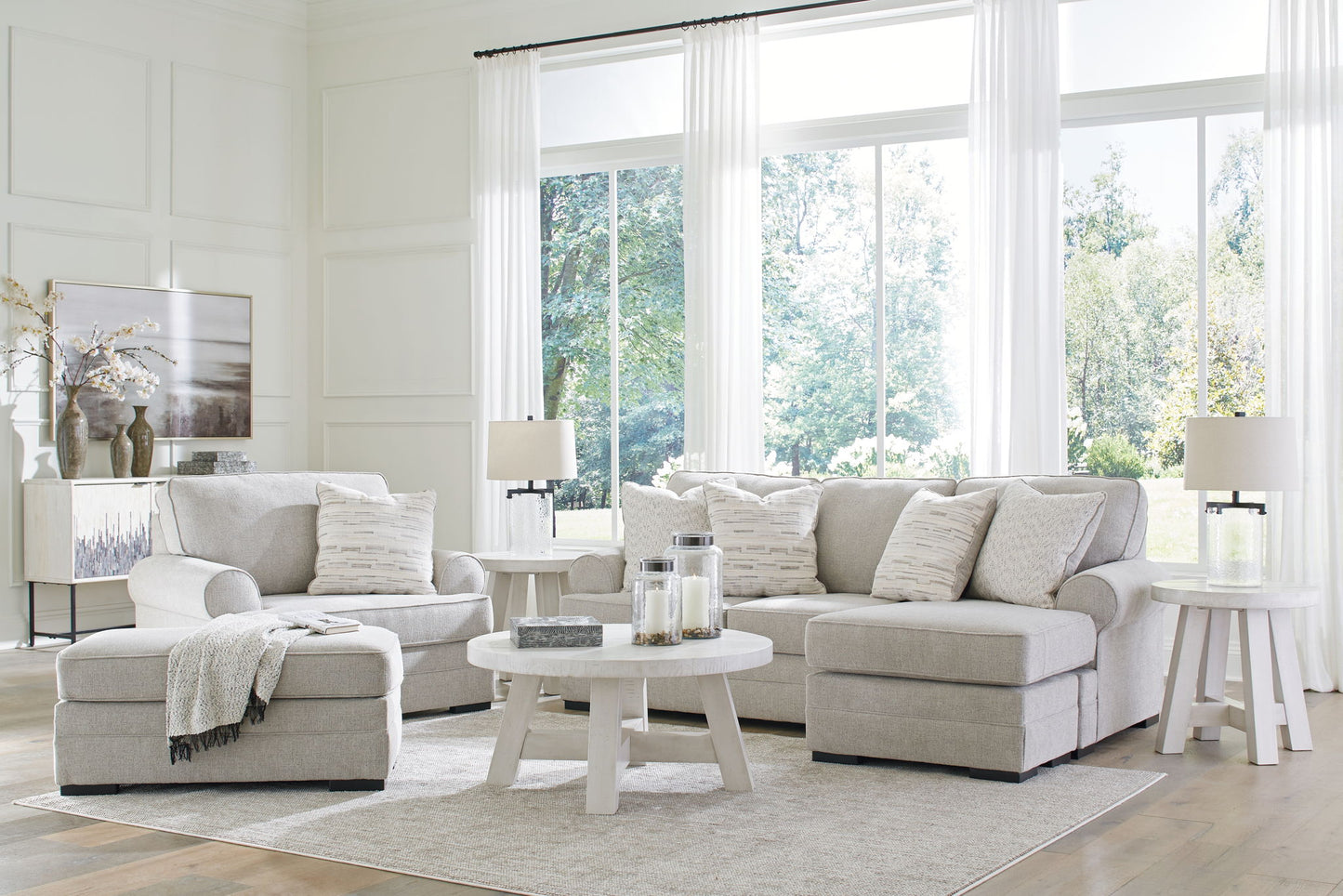 Light gray sofa set in a bright living room with large windows.